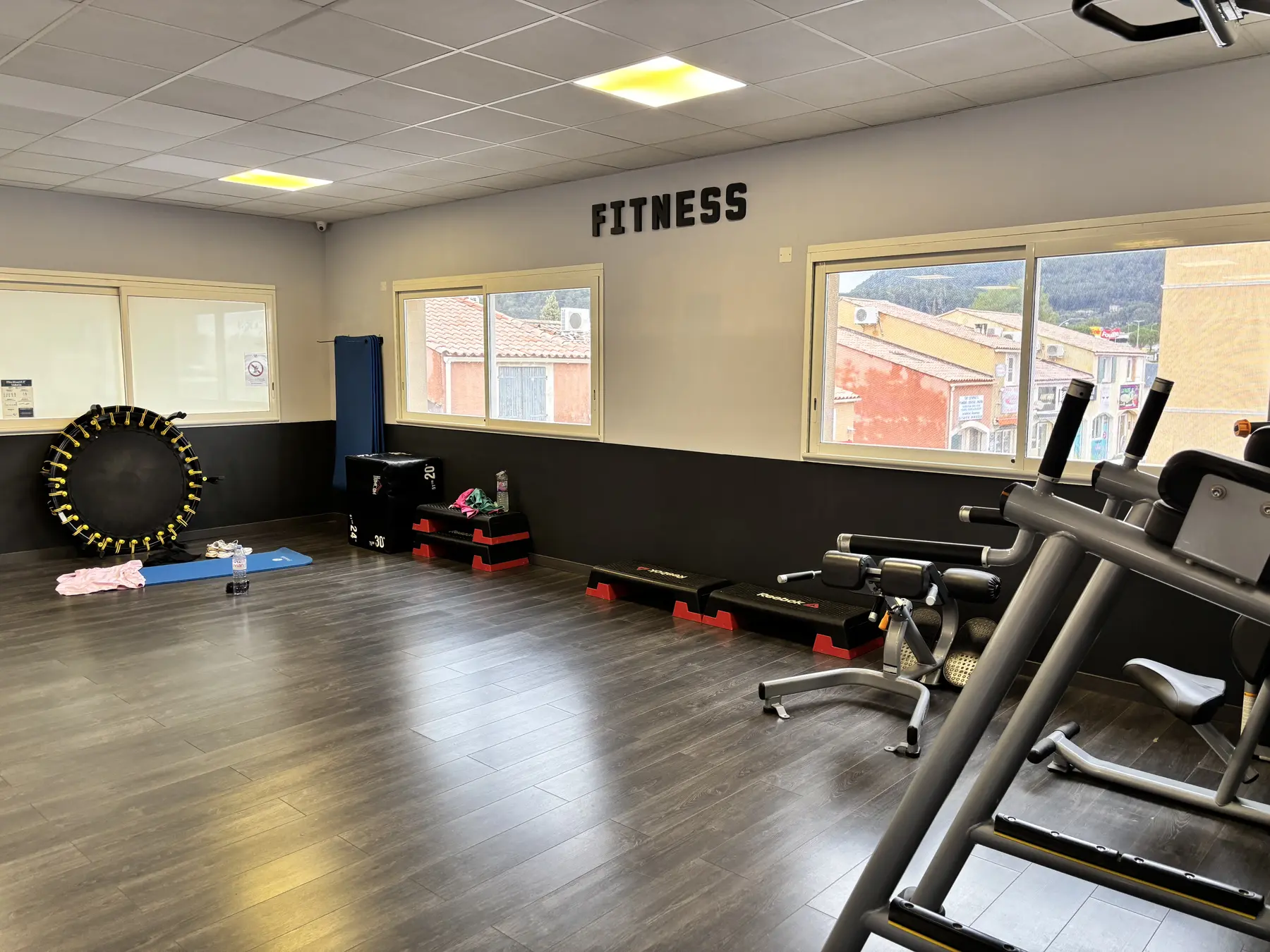 Espace fitness lumineux avec tapis de course et petit matériel